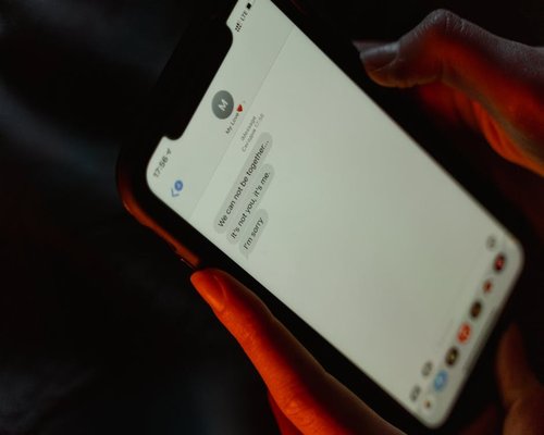 Close up of a mobile phone screen displaying messages in a dimly lit room