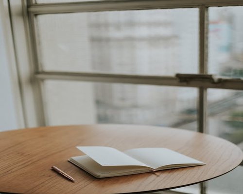 A notebook and pen on a table next to a window