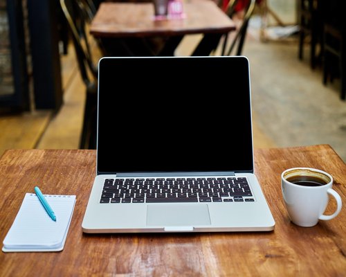 A well lit workspace in a modern cafe with coffee and notebooks