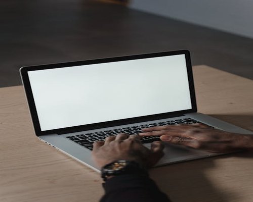 A person typing on a laptop computer on a minimalist wooden desk